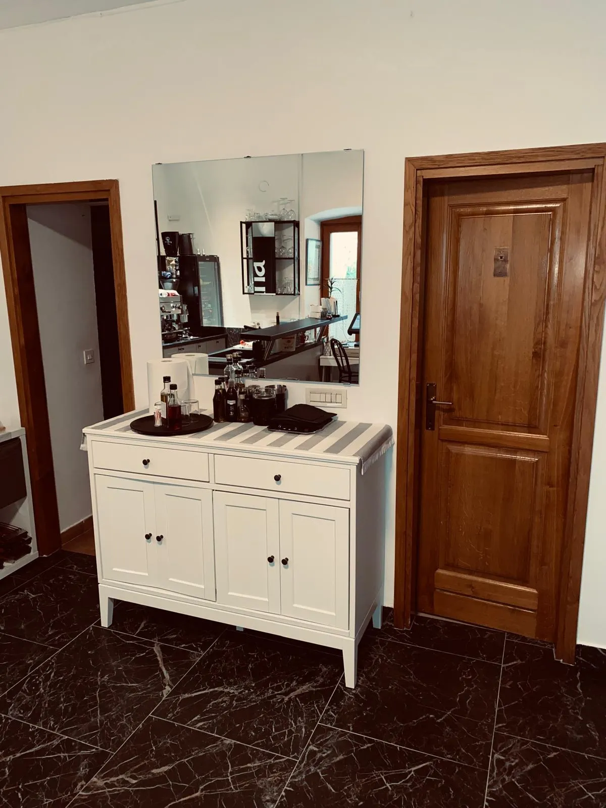 A cosy interior corner — a white sideboard and mirror beside a solid wood door