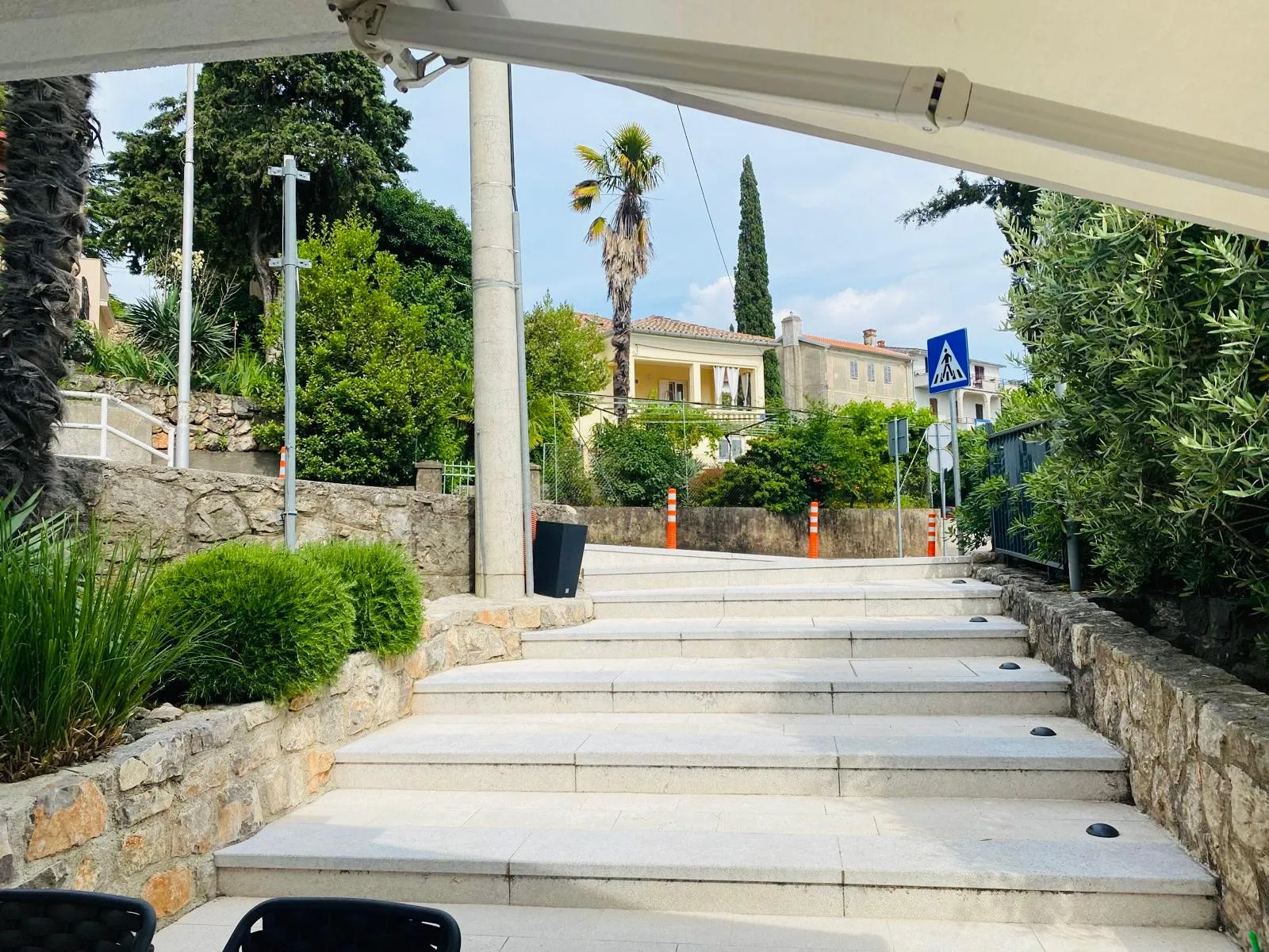 The view from the terrace up the stone garden steps, with palms, cypress and a Mediterranean villa beyond